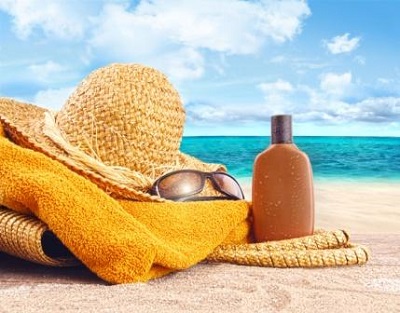 Suntan lotion, straw hat with towel at the beach